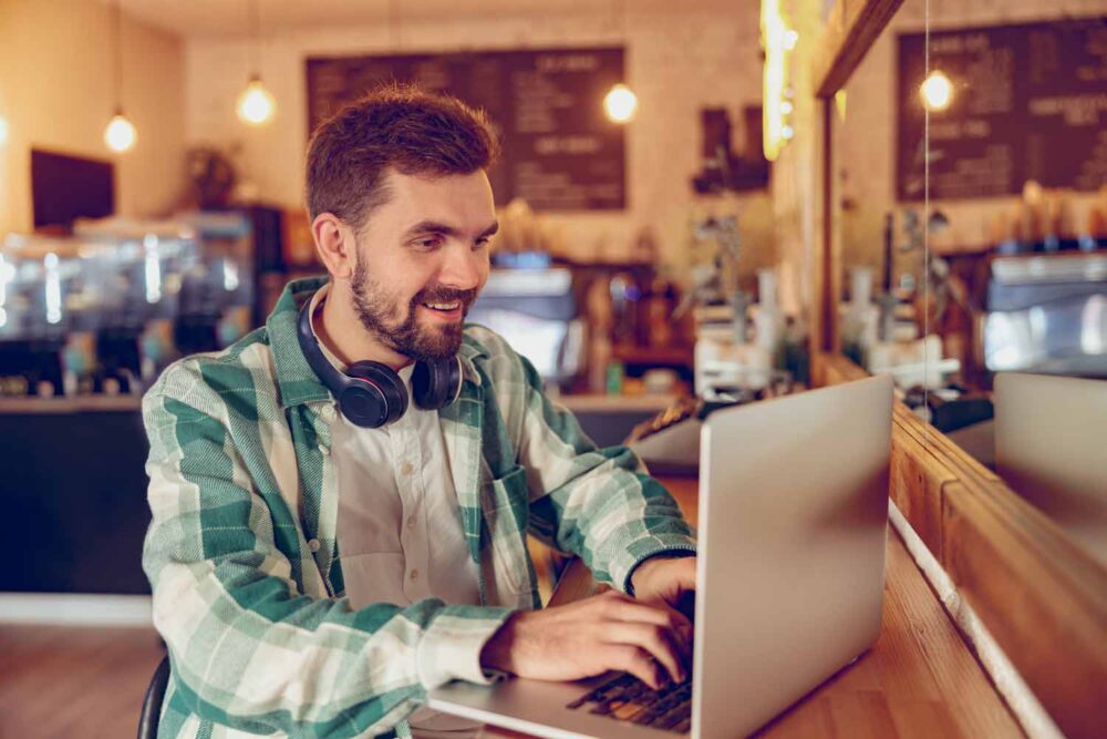 cheerful bearded man working on laptop in cafeteri 2022 02 23 02 57 27 utc