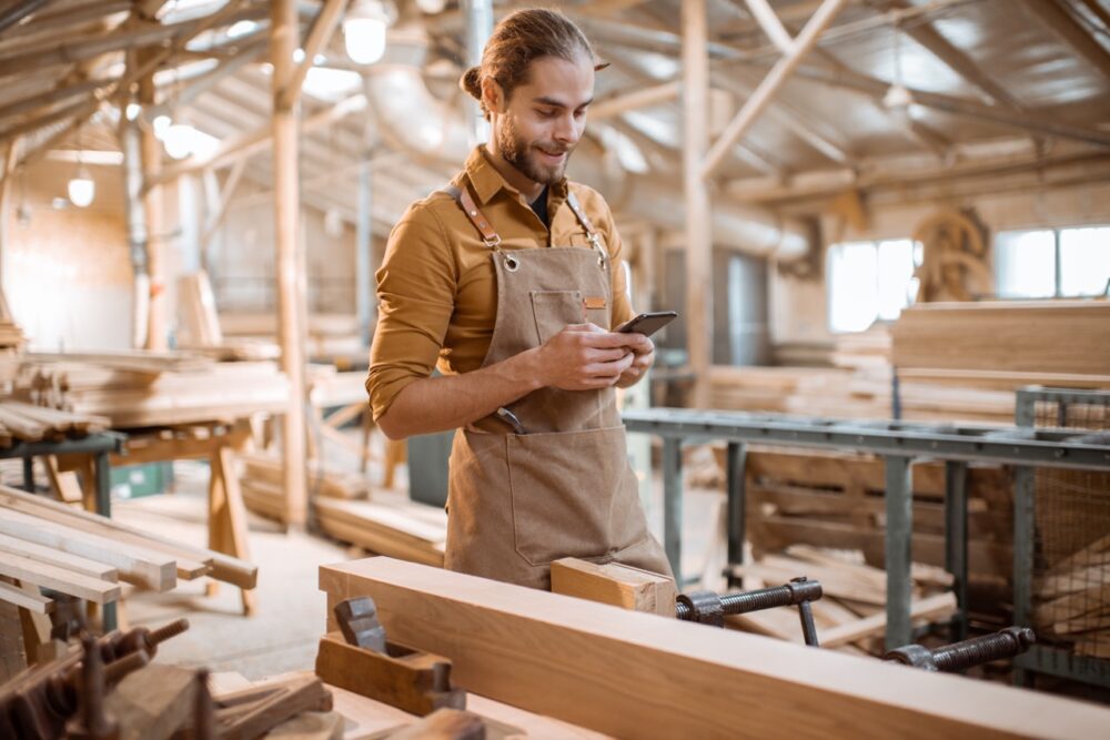 carpenter with phone in the workshop 2023 11 27 05 06 06 utc Large