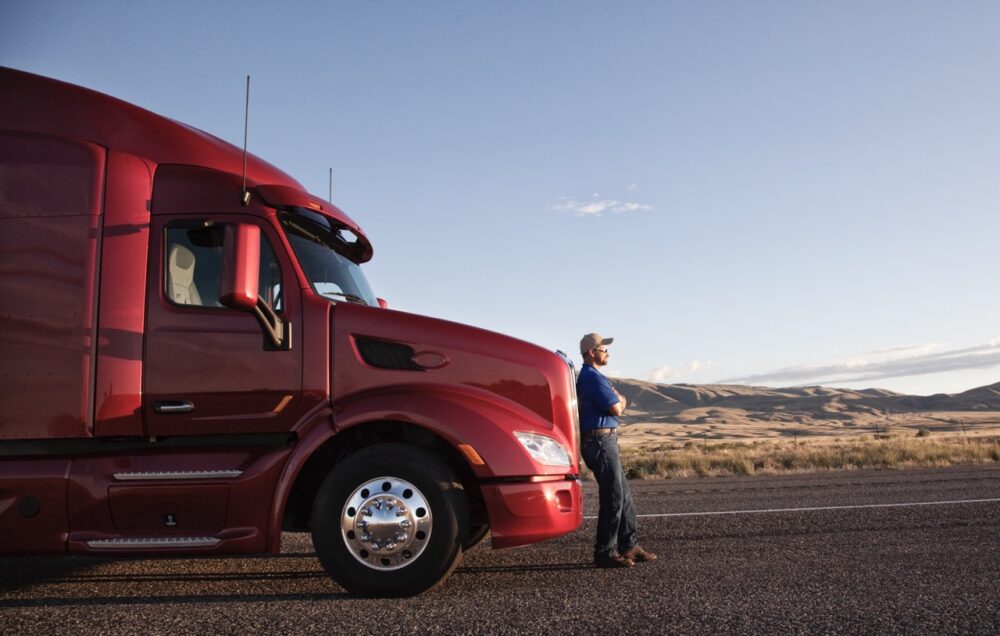 truck driver leaning on the grill of his commercia 2023 11 27 05 21 04 utc Large