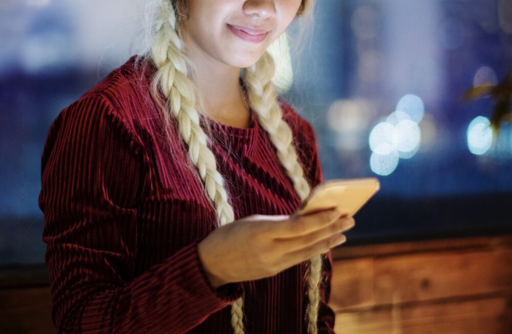 smiling young woman using a smartphone in the even 2023 11 27 05 14 14 utc Large