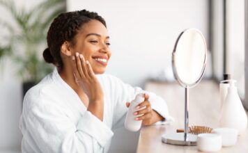 woman applying lotion smiling at mirror indoors 2026 01 08 23 22 00 utc Large