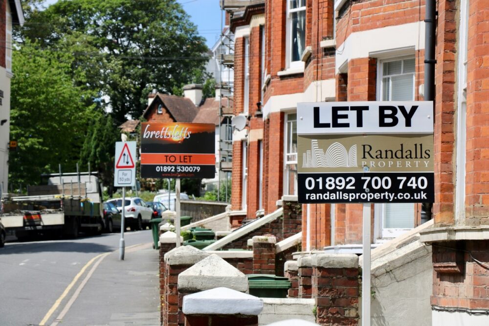 A "Let" property sign displayed in a shop window, representing a rental property in the UK private rented sector.