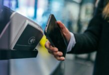 Shopper holding a smartphone against a contactless card payment terminal