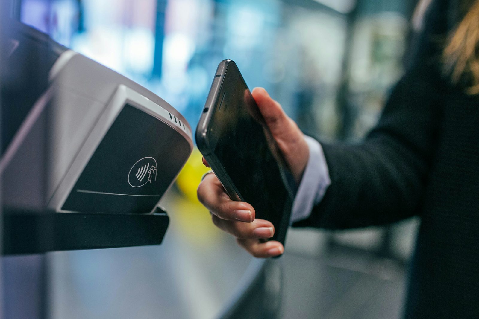 Shopper holding a smartphone against a contactless card payment terminal