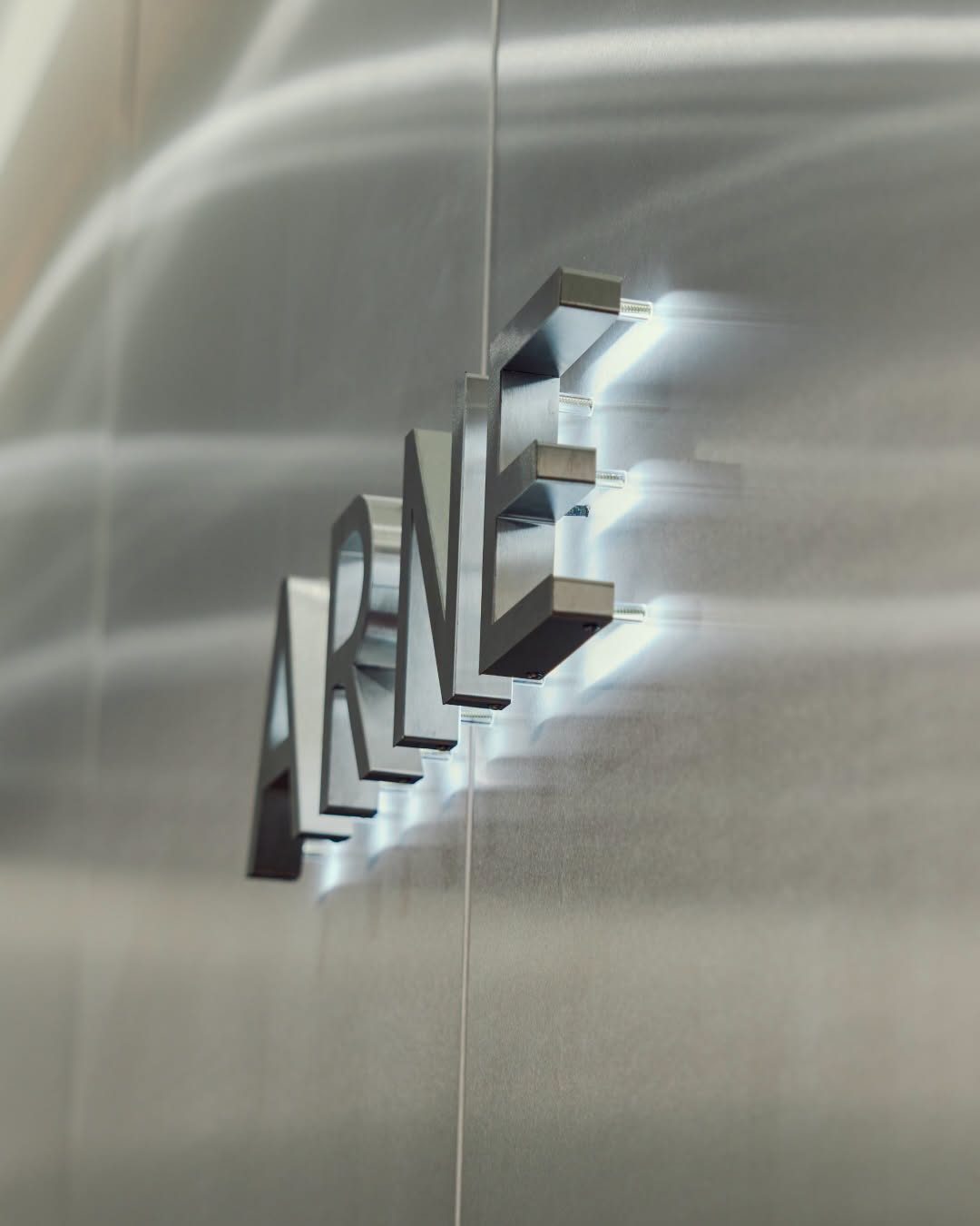 ARNE lettering mounted on a brushed steel wall