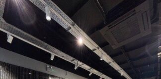 Designer menswear store interior with rails of jackets and knitwear on dark marble-effect plinths, herringbone wood flooring and track lighting