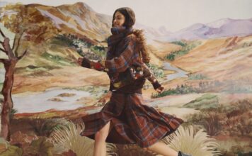 Model in a brown and blue tartan knit with floral embroidery and a tartan pleated skirt, running in front of a painted landscape backdrop