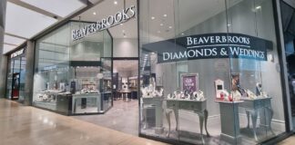 Beaverbrooks store frontage in a shopping centre, with illuminated signage, a Diamonds & Weddings window of jewellery displays and a TAG Heuer store next door