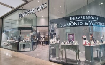Beaverbrooks store frontage in a shopping centre, with illuminated signage, a Diamonds & Weddings window of jewellery displays and a TAG Heuer store next door