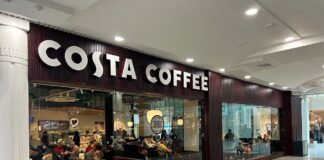 Costa Coffee frontage inside The Liberty shopping centre, with customers seated behind full-height glazing and a Freshly Baked Pastries sign