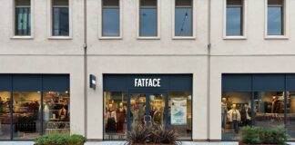 FatFace shopfront with a navy fascia and window displays of winter clothing, with planters on the paving outside