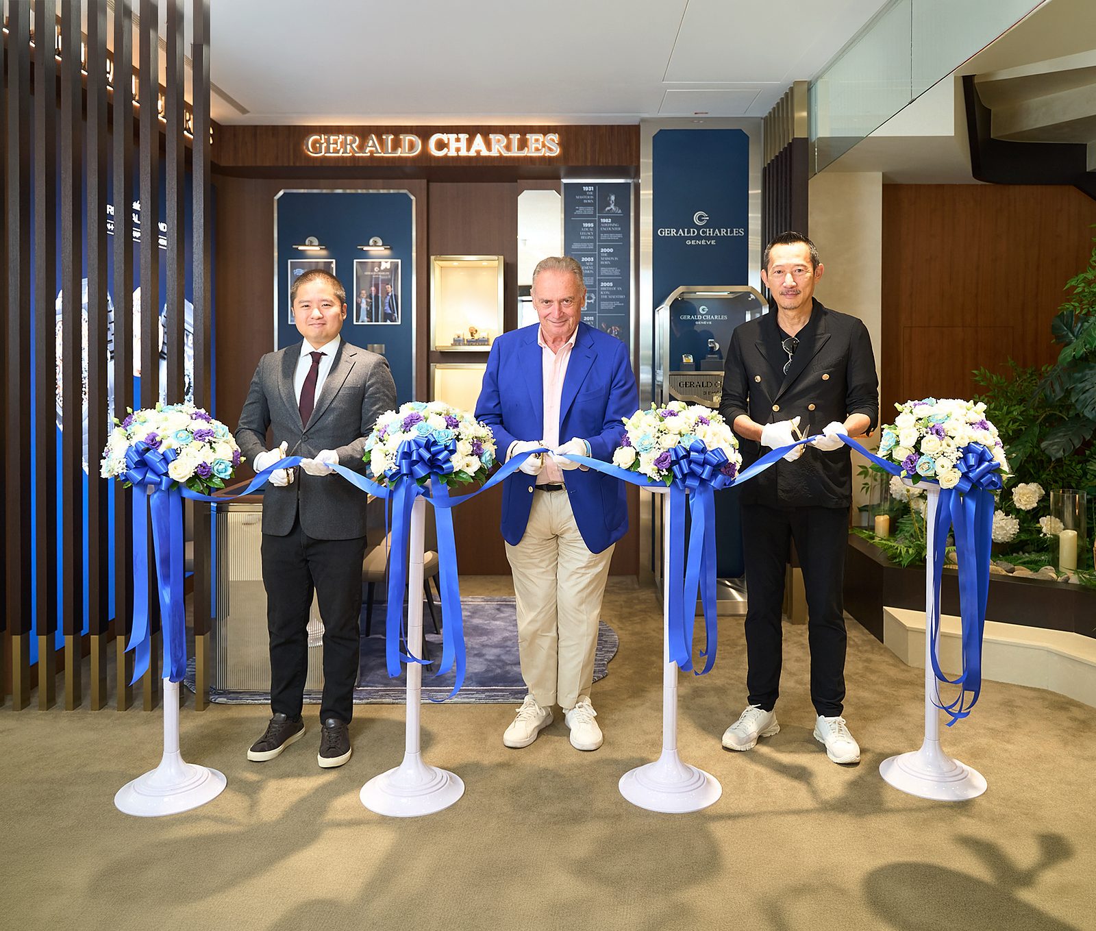 Three men at the ribbon-cutting ceremony for the Gerald Charles shop-in-shop in Taipei, with blue ribbons and floral displays