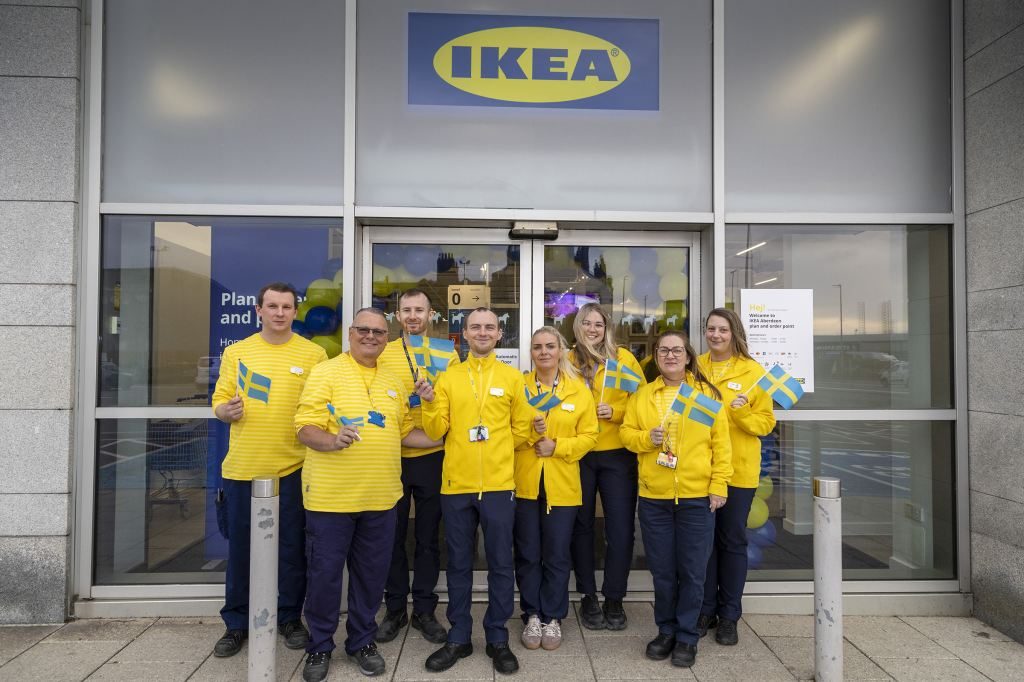 IKEA co-workers in yellow uniforms holding Swedish flags outside the entrance to the IKEA Aberdeen Plan and Order Point