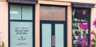 kate spade new york to Open at Cotswolds Designer Outlet Shopfront of the forthcoming kate spade new york store at Cotswolds Designer Outlet, with window graphics announcing a November 2026 opening and a campaign image of pink shoes and a pink handbag
