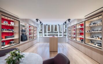 Leica Opens New UK Flagship Store in Mayfair Room at Leica Store London Mayfair lined with red-backed glass cabinets of Leica cameras and lenses, with a central display plinth, bay windows and a marble table