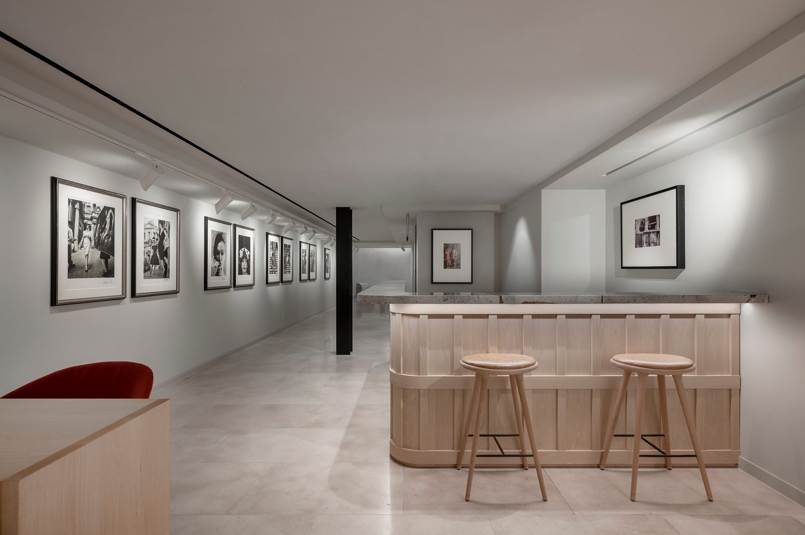 Gallery space at Leica Store London Mayfair with framed black-and-white photographs and an oak-panelled bar with two stools