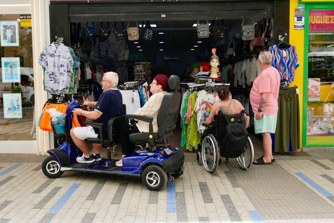 People in wheelchairs and mobility scooters outside shop