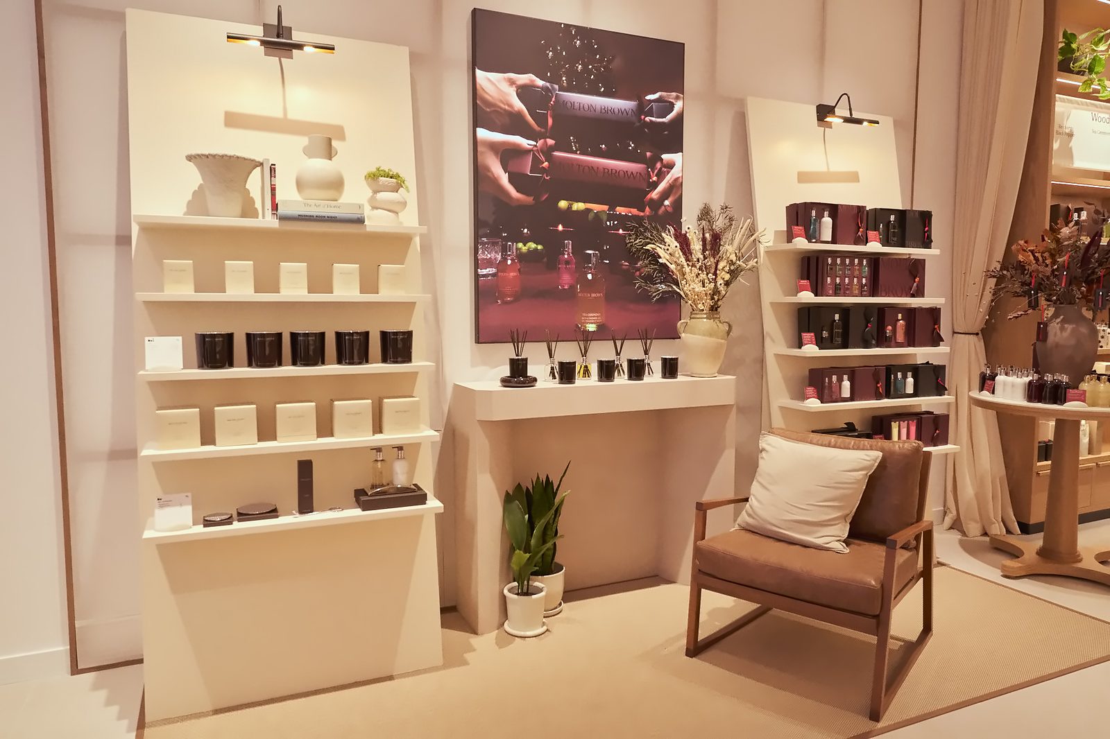 Home fragrance display with candles, reed diffusers and gift sets beside a leather armchair at the Molton Brown Scent Pavilion