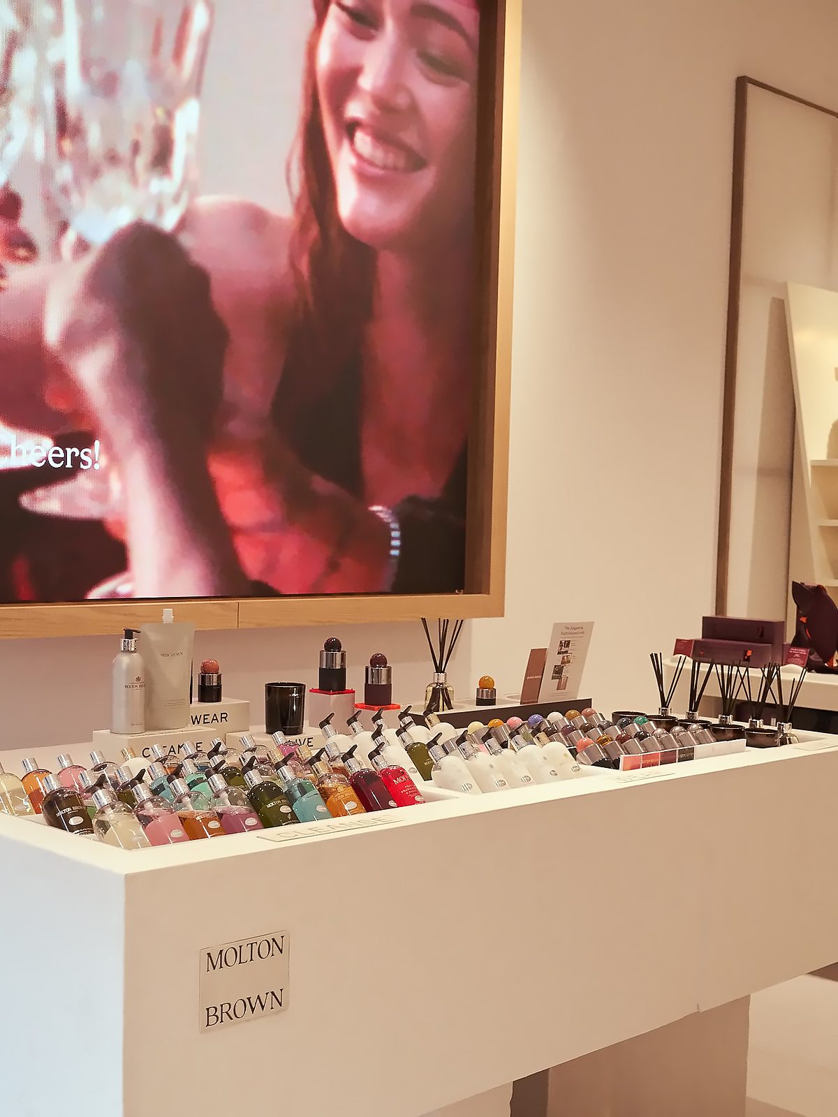 Table of Molton Brown bath and body products grouped under Cleanse, Wear and Live beneath a large screen