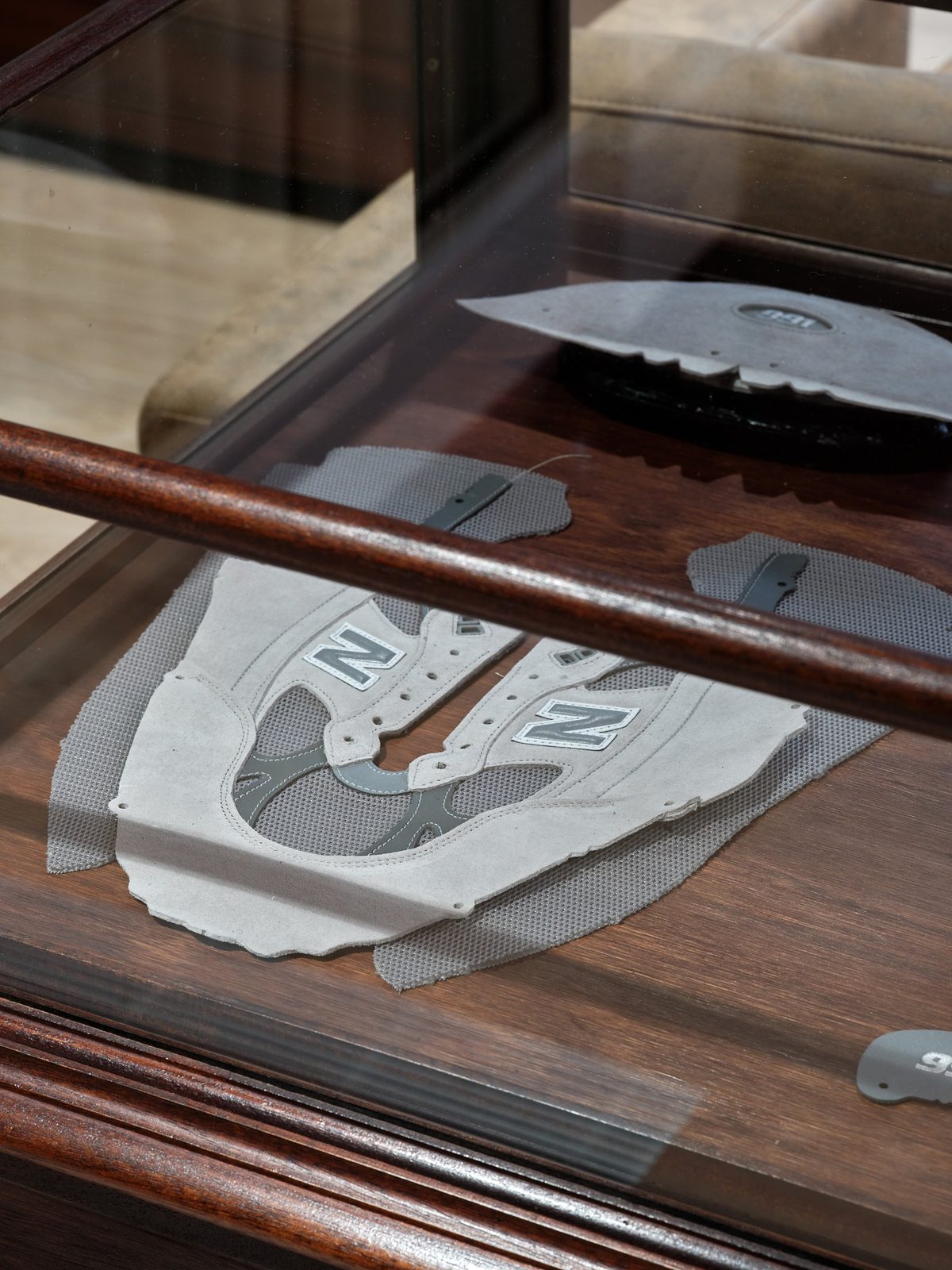 Close-up of New Balance shoe upper components displayed inside a wooden and glass case