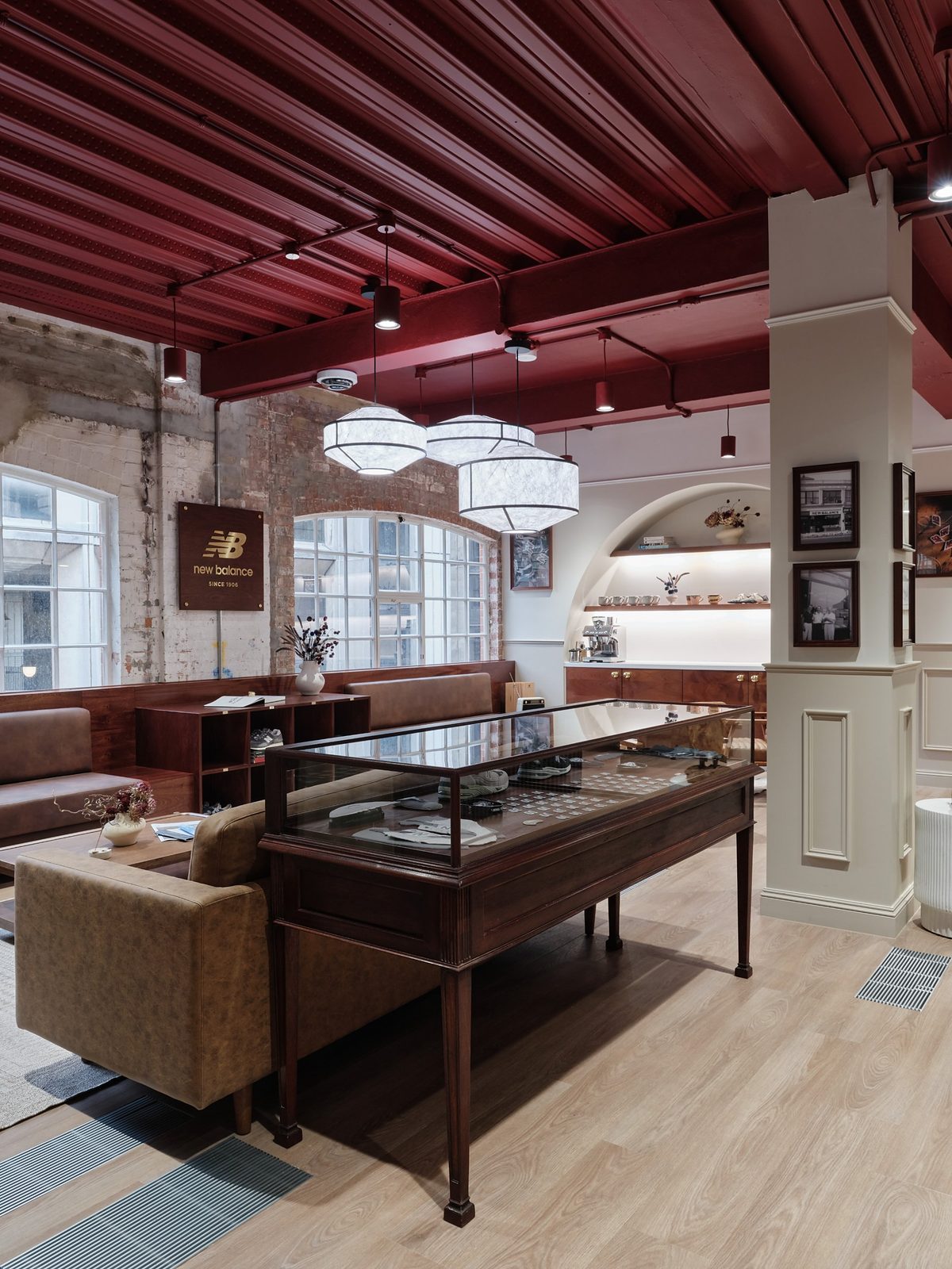 Glass-topped wooden display case and leather seating beneath a burgundy beamed ceiling and paper pendant lights