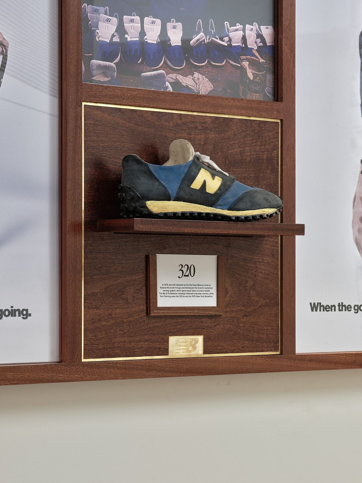 Vintage New Balance 320 trainer displayed on a wooden shelf in a frame with a descriptive plaque