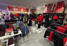 Inside the refurbished New Look store at Cribbs Causeway, with mannequins, rails of red and black partywear, an accessories table and campaign imagery above slatted wall panels