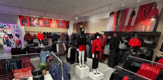 Inside the refurbished New Look store at Cribbs Causeway, with mannequins, rails of red and black partywear, an accessories table and campaign imagery above slatted wall panels