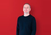Nikk Smith, Sales Director at Pixel Inspiration, smiling against a red background