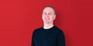 Nikk Smith, Sales Director at Pixel Inspiration, smiling against a red background