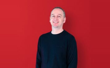 Nikk Smith, Sales Director at Pixel Inspiration, smiling against a red background