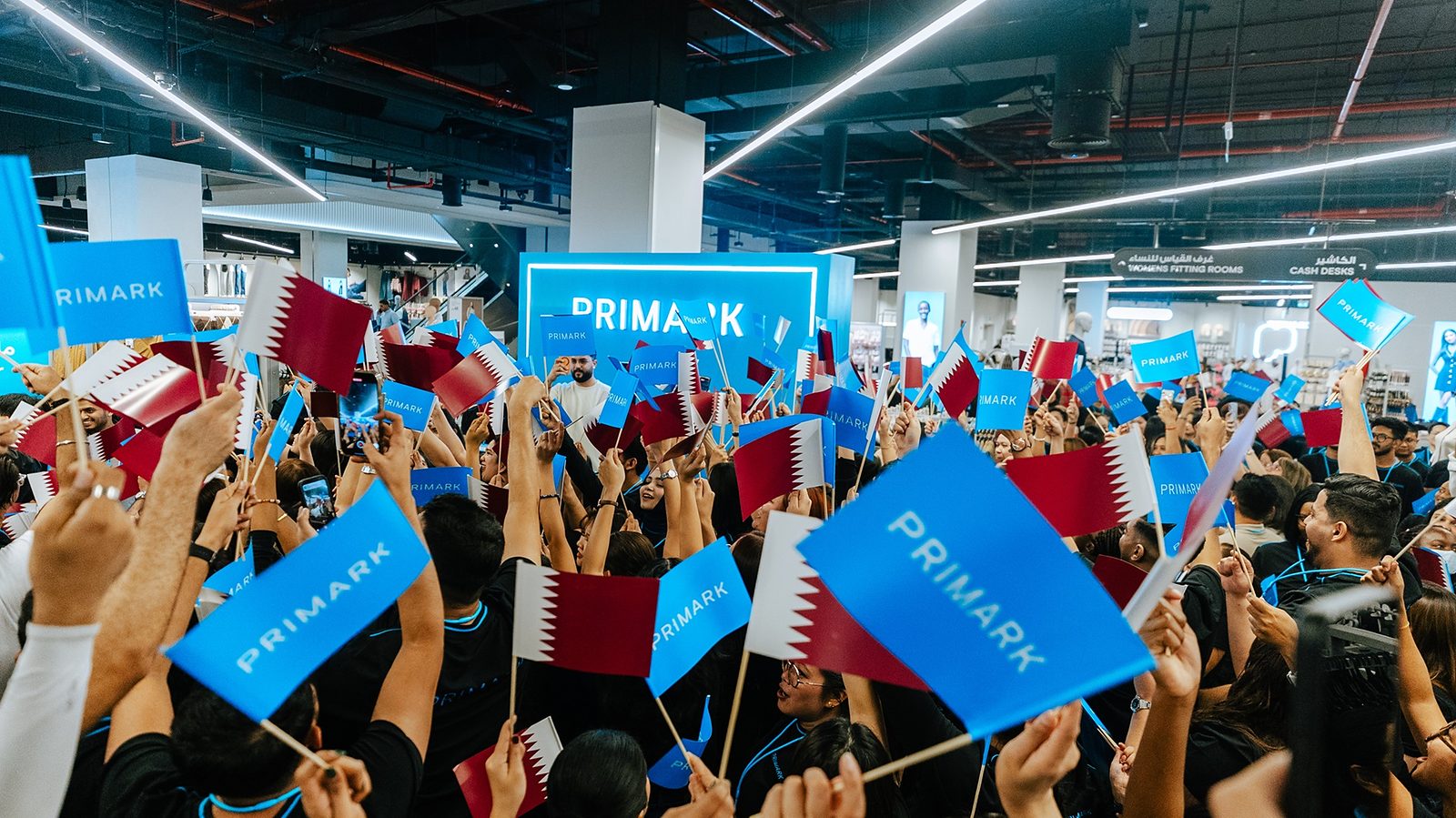 Crowd waving Primark and Qatar flags inside the store during the opening celebrations