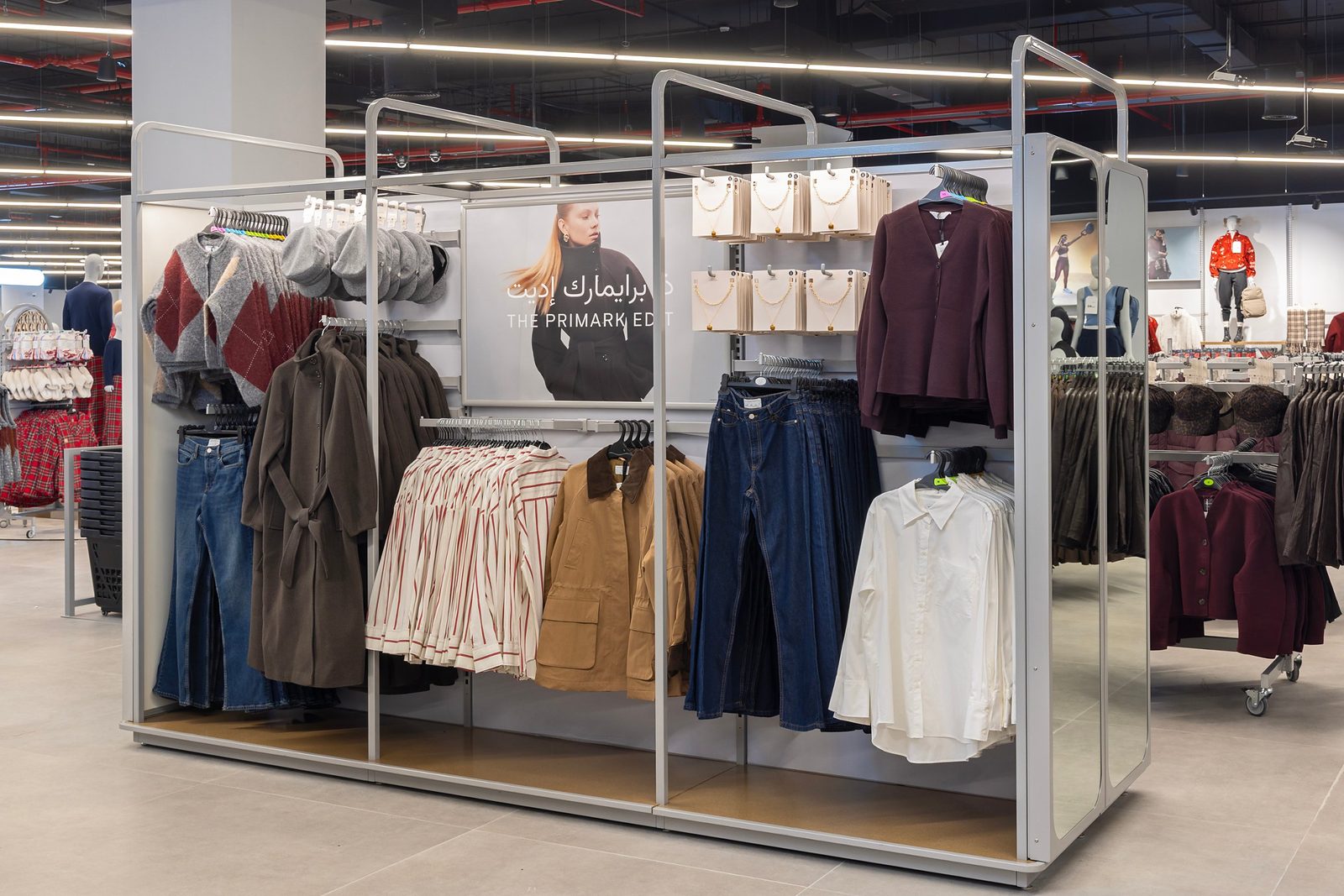 The Primark Edit fixture with coats, knitwear, denim and jewellery, signed in English and Arabic