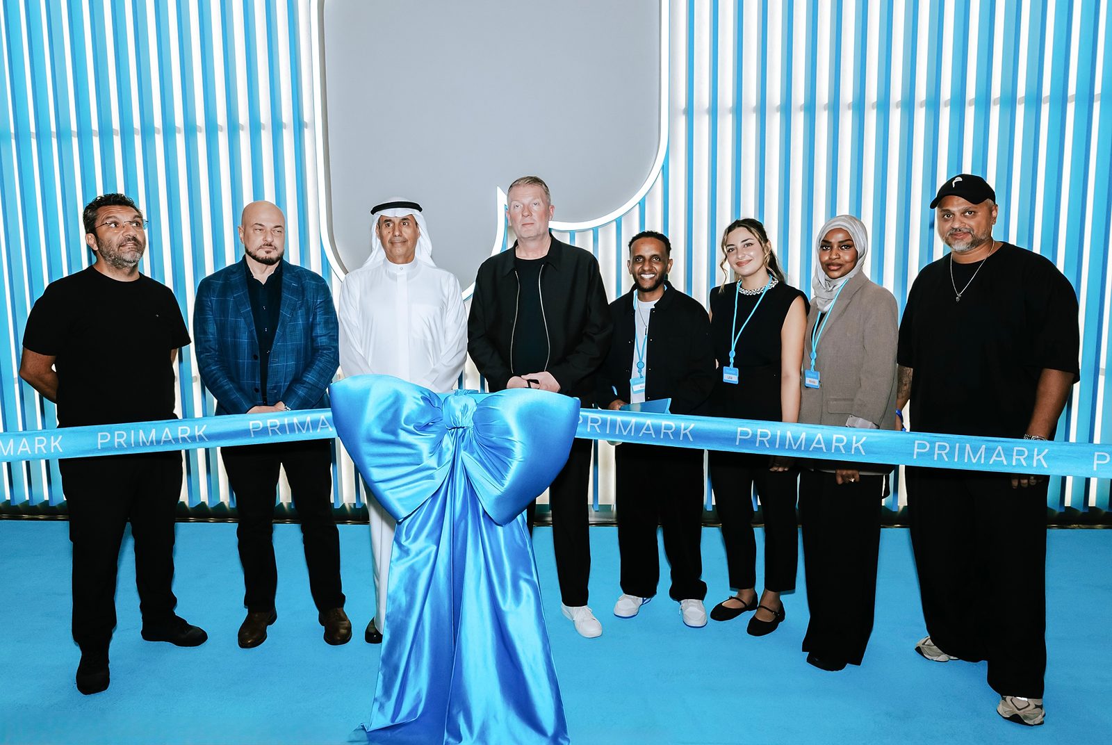 A group gathered behind a Primark ribbon with a large blue bow at the store opening