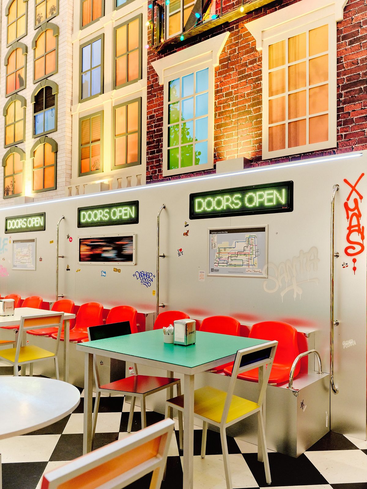Red seats and a green table inside the Downtown Café's subway carriage, beneath Doors Open signs and a store map styled as a subway map