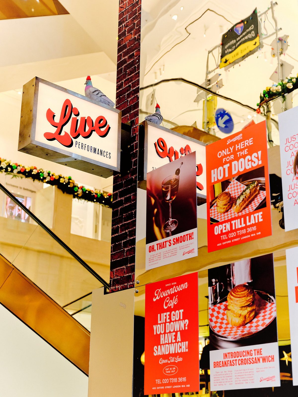 A Live Performances lightbox sign beside Downtown Café posters advertising hot dogs, sandwiches and cocktails