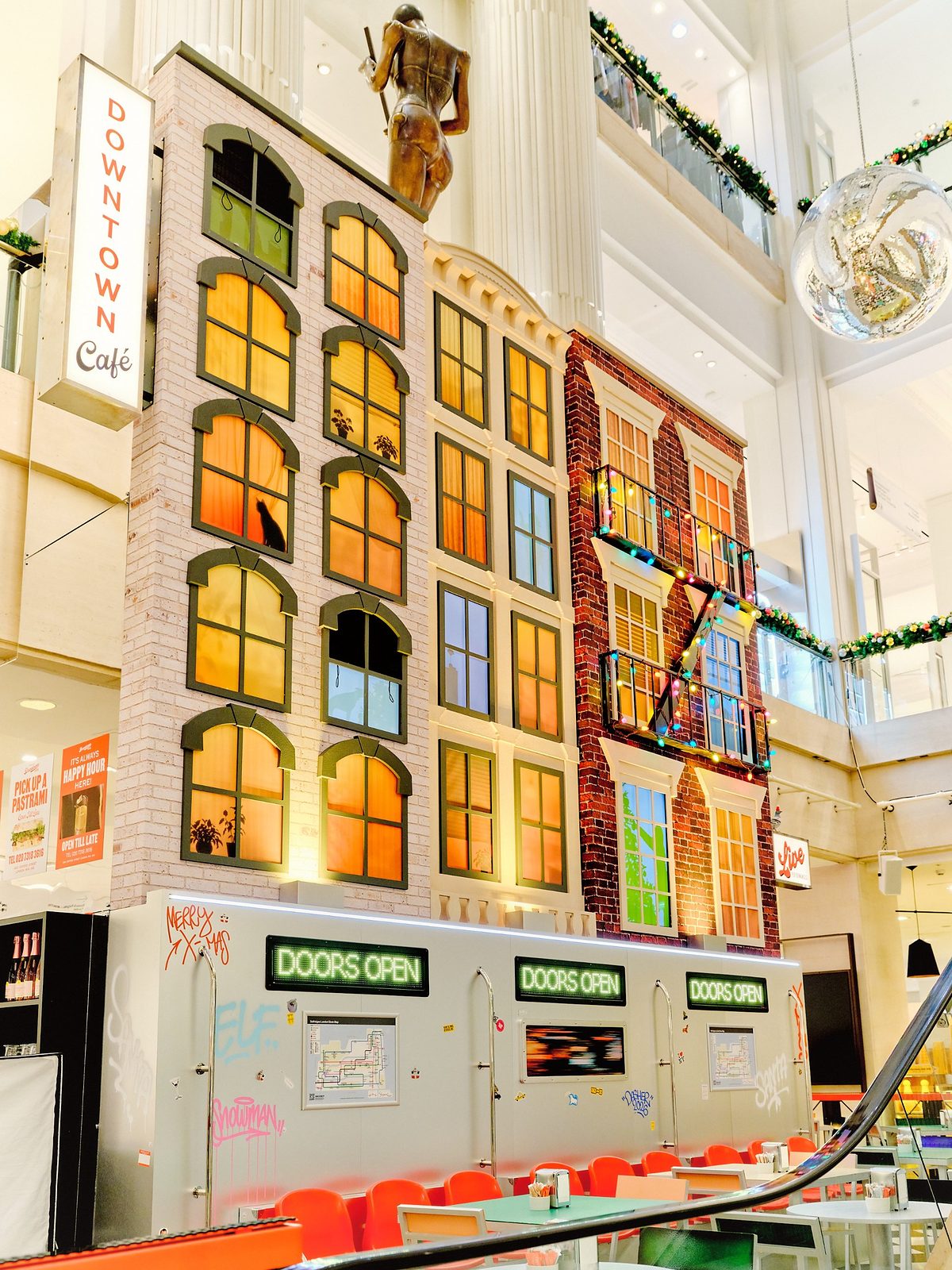 The Downtown Café at Selfridges London, with New York-style building facades above a subway carriage and red seating