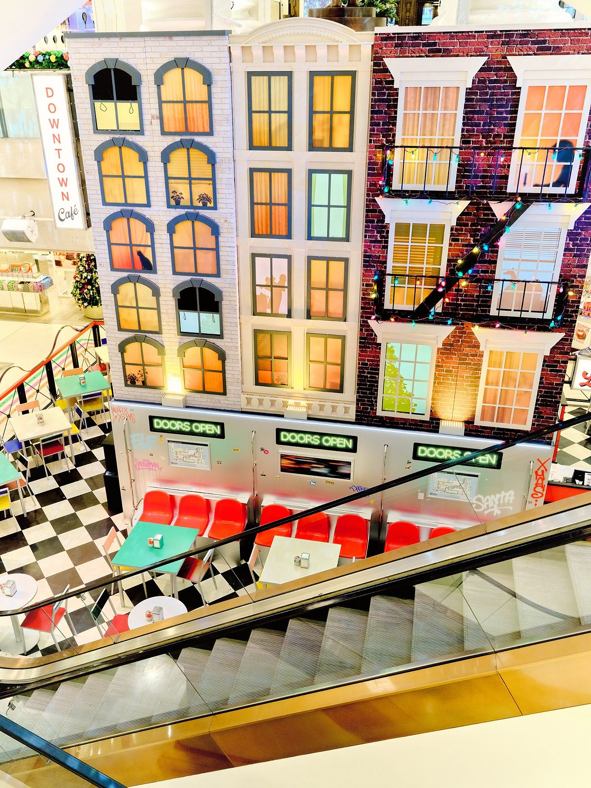 Overhead view of the Downtown Café, with a black and white chequered floor, subway carriage seating and an escalator
