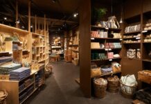 Søstrene Grene store interior with wooden shelving stacked with textiles, baskets, candles and storage boxes under pendant lights