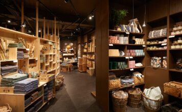 Søstrene Grene store interior with wooden shelving stacked with textiles, baskets, candles and storage boxes under pendant lights