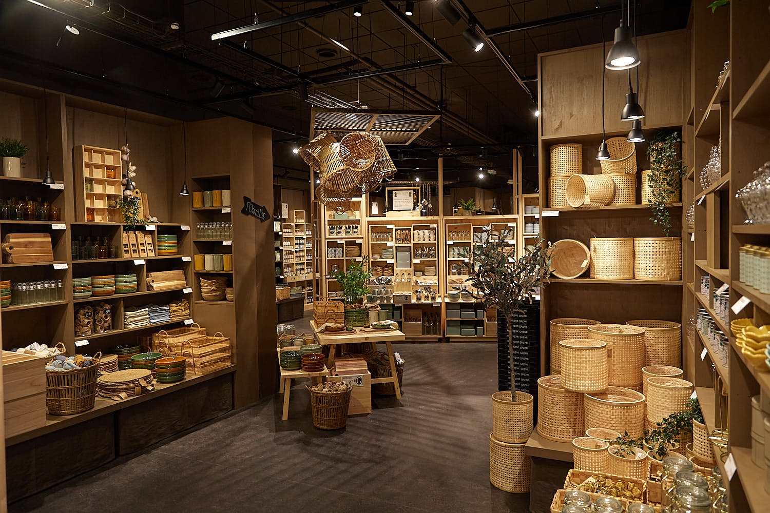 Søstrene Grene store interior with rattan baskets, ceramics and glassware on wooden shelves and display tables