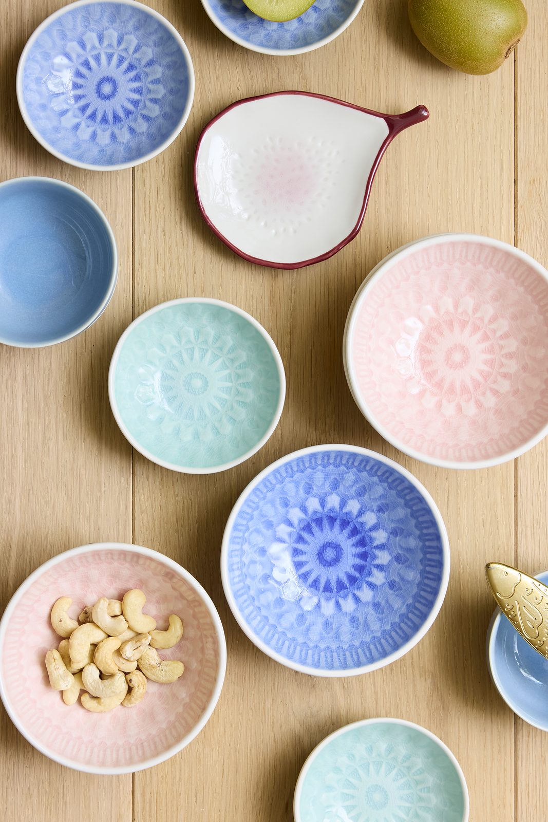 Søstrene Grene ceramic bowls in blue, pink and mint with embossed patterns, arranged on a wooden table
