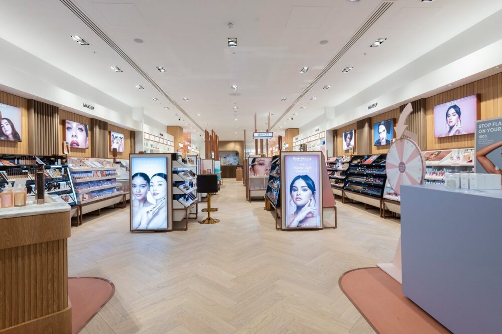 Interior of a Space NK store, with make-up and skincare fixtures, illuminated brand displays and herringbone timber flooring