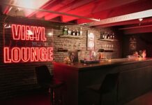 Red Vinyl Lounge neon sign beside the bar counter and stools at UMusic Shop Camden