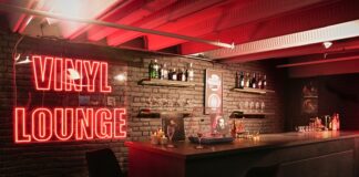 Red Vinyl Lounge neon sign beside the bar counter and stools at UMusic Shop Camden