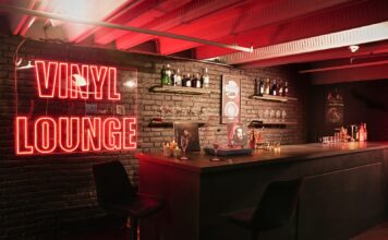 Red Vinyl Lounge neon sign beside the bar counter and stools at UMusic Shop Camden