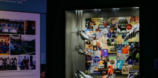 Display case of adidas football boots and balls in front of a collage of Chelsea FC memorabilia, beside a panel on Chelsea’s shirt sponsors