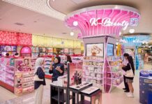 Pink illuminated K-Beauty zone at Watsons Plus, with a staff member helping a customer at a make-up display nearby